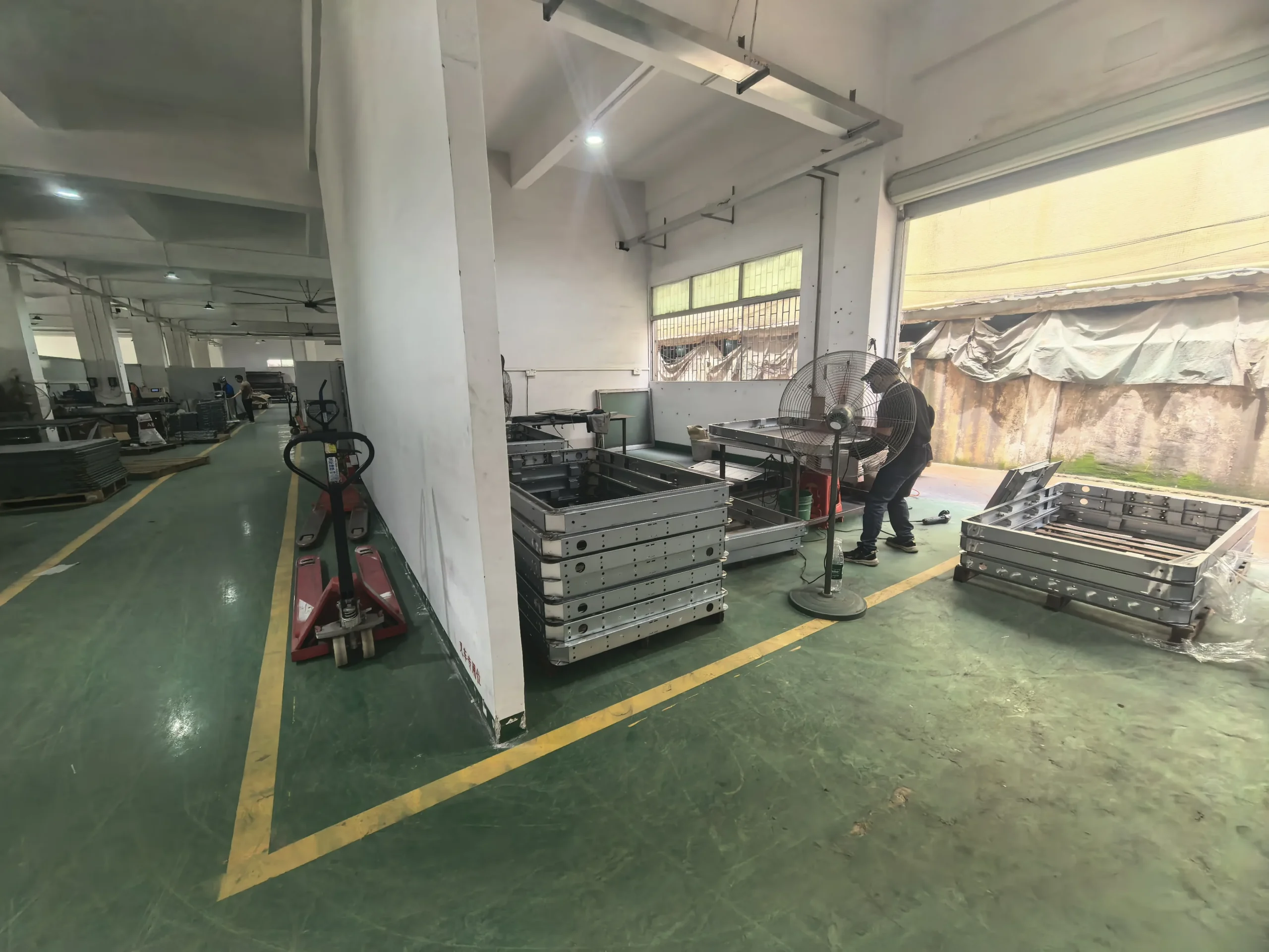 Workers performing sheet metal grinding and surface finishing on fabricated display components.